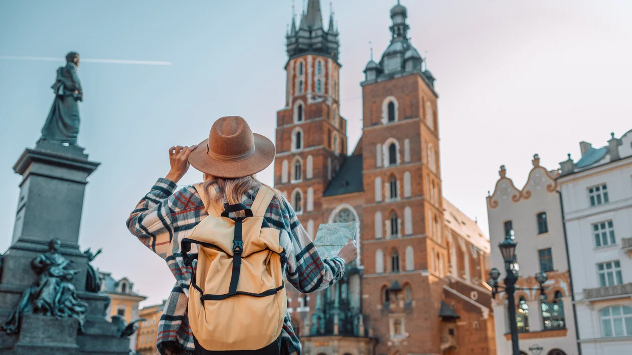 Traveler with backpack and map facing a historic cathedral in a European city square.