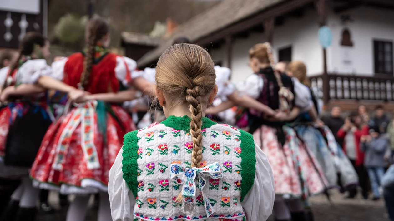 Girls in traditional folk dresses dancing in a circle outdoors.