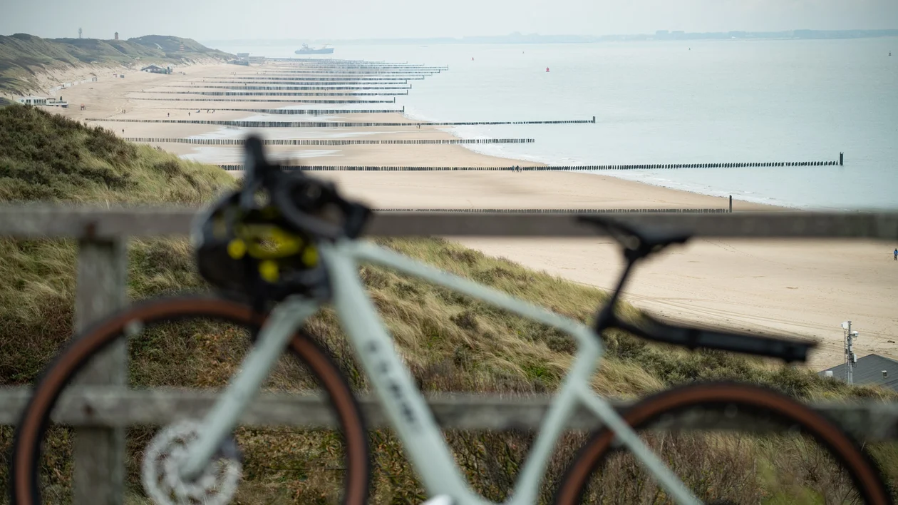 Blurry bicycle in front of a sandy beach and calm sea on a cloudy day.