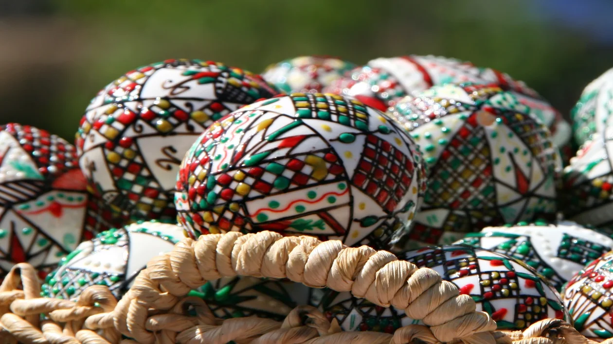 Colorful, intricately patterned balls in a woven basket outdoors.