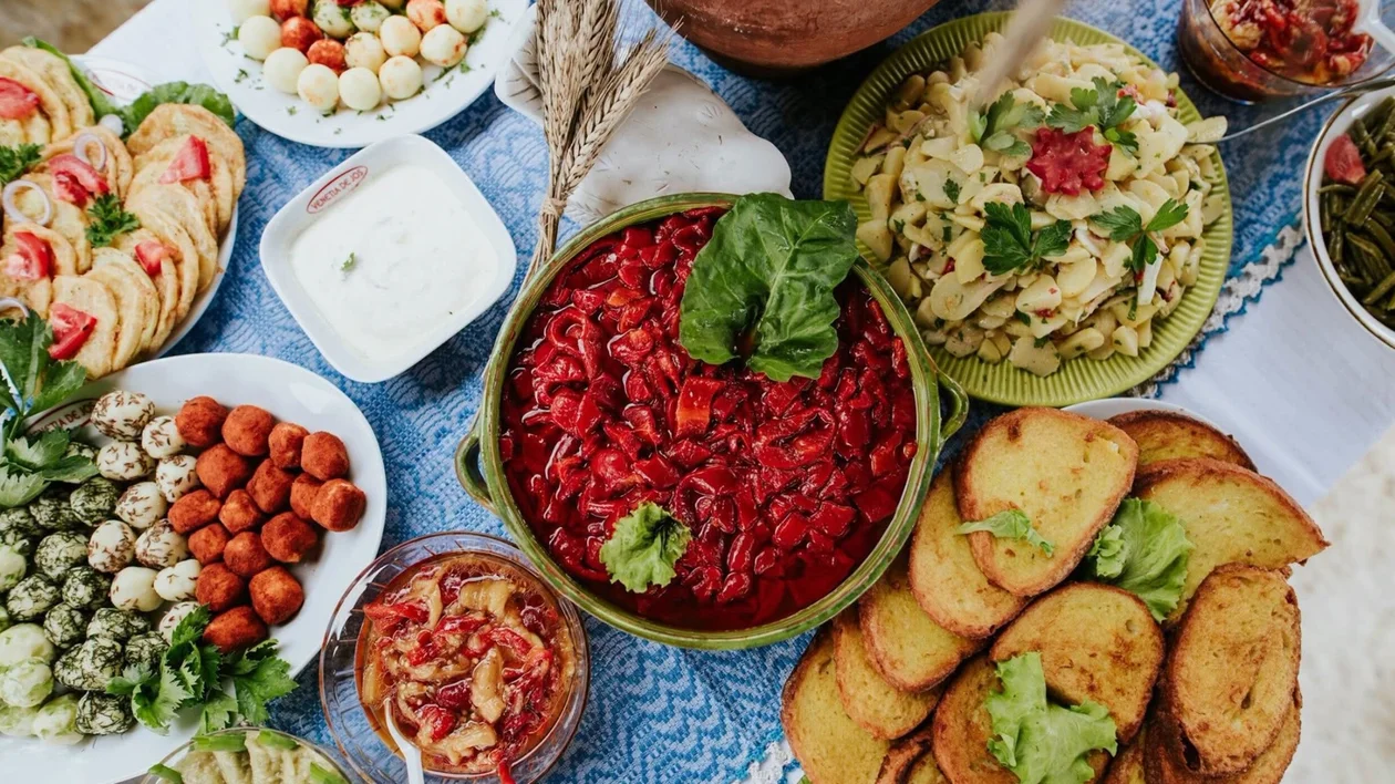 Assorted dishes on a table, including salads, bread, dips, and colorful vegetables.