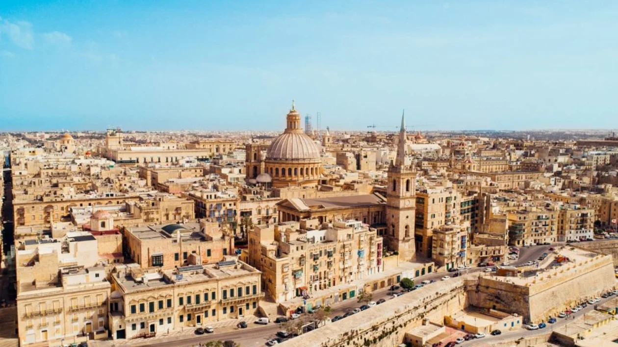 Aerial view of a historic Mediterranean city Valletta with domed churches and tan stone buildings.