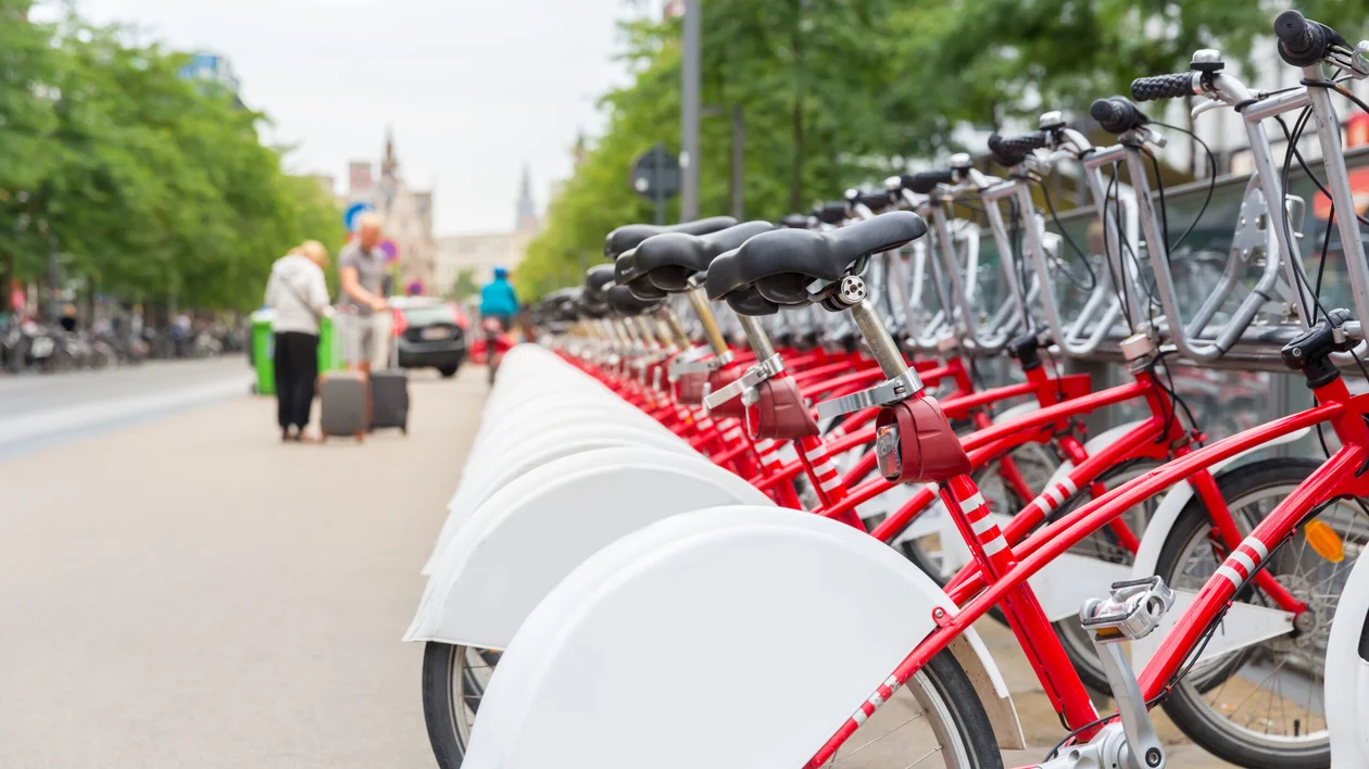 Row of red rental bicycles lined up on a city street.