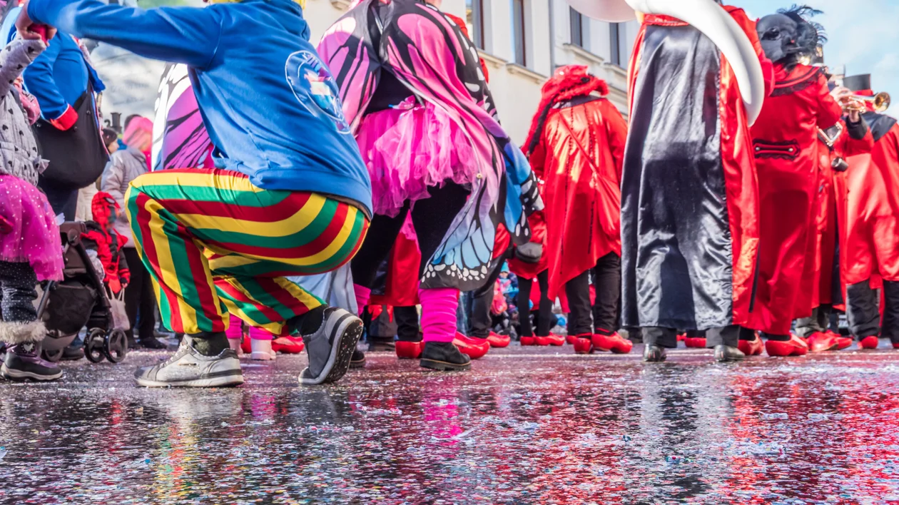 People in colorful costumes and bright clothing during a vibrant outdoor parade.