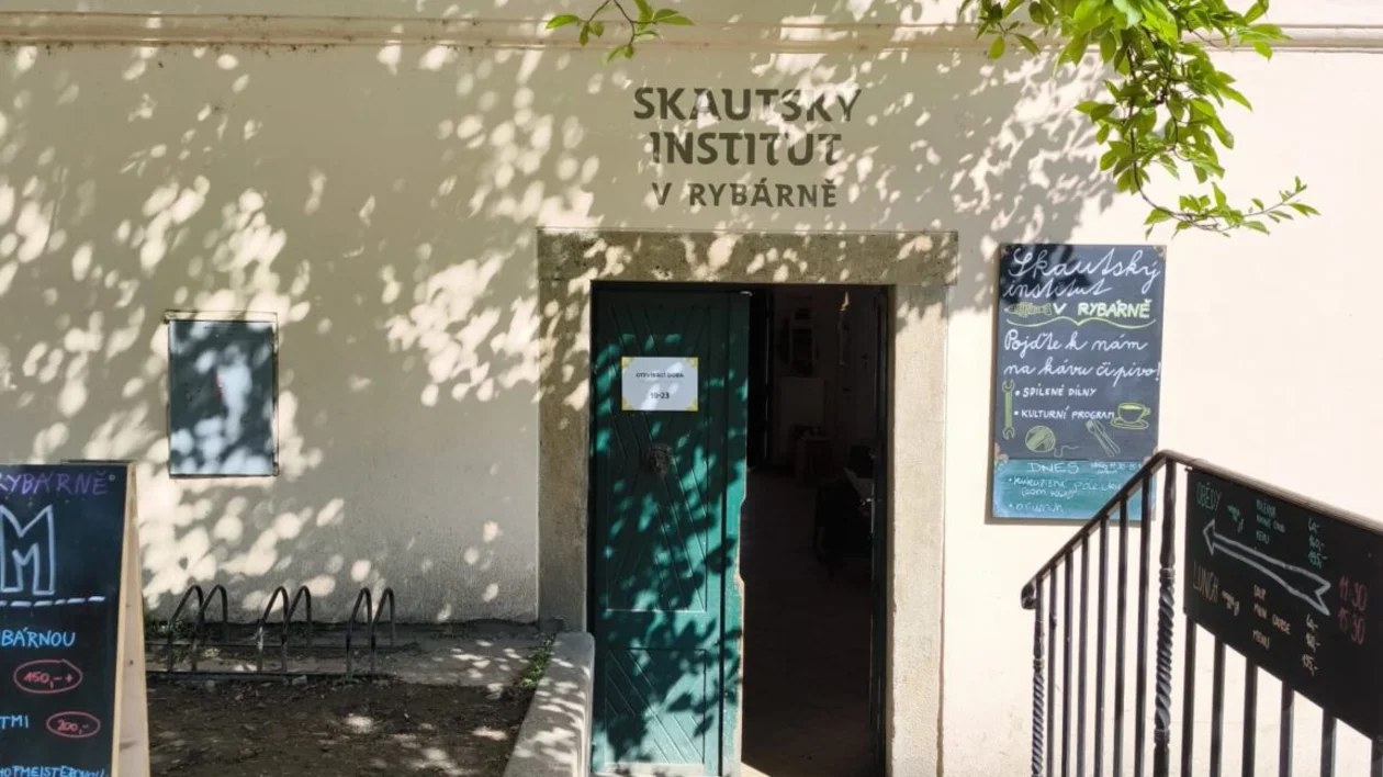 Entrance to a building with a green door, shaded by leafy branches.