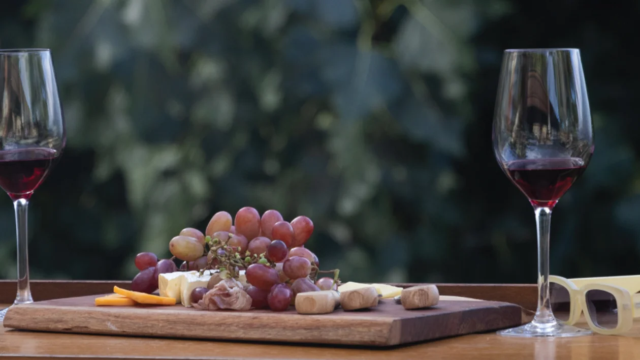 Two glasses of Cypriot red wine with grapes and local food on a wooden board