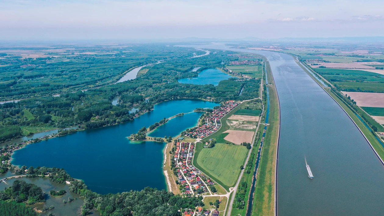 Aerial view of a river, lakes, green fields, and a village with houses.