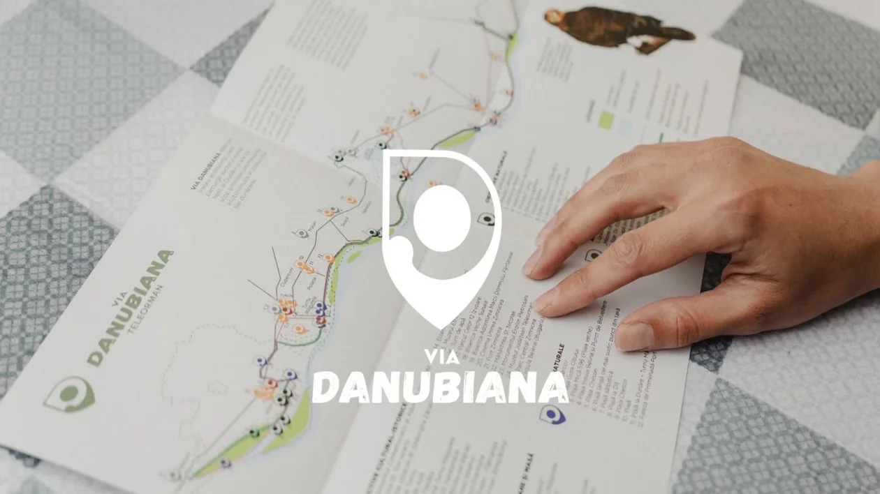 Hand holding a map brochure on a checkered table, with Danubiana logo overlay.