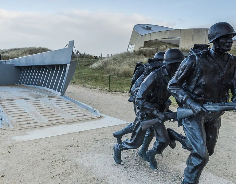 A monument of two soldiers and a tank in memory of the events in Omaha beach