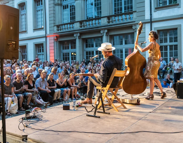 Two musicians are performing on a public stage