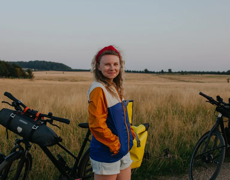 A smiley girl with her bike in the fields