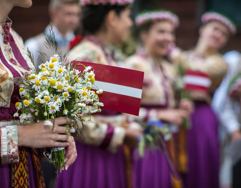 Midsummer celebrations in Riga with the Latvian flag and a group of women showcasing the folklore traditions.