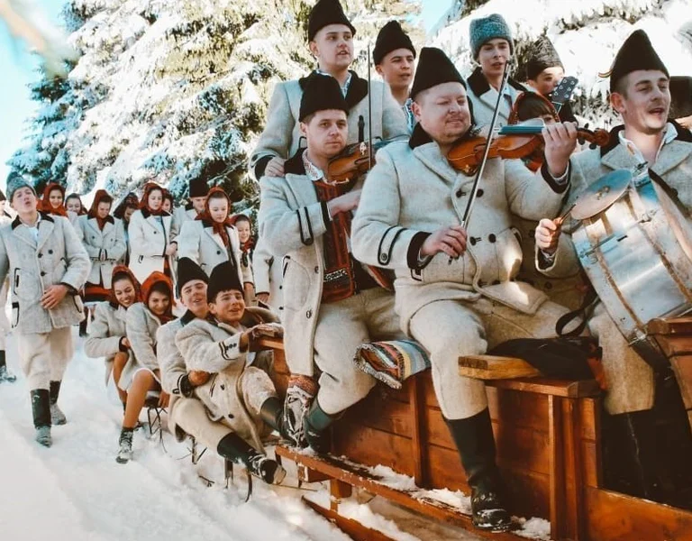 Group in traditional attire playing musical instruments on a sleigh in a snowy forest.