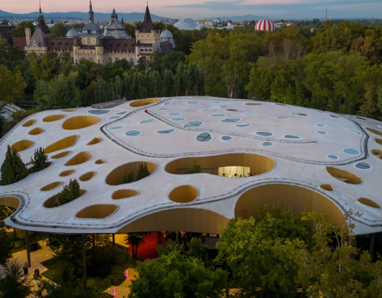 Aerial view of a modern, organically shaped building with numerous oval holes in its roof.