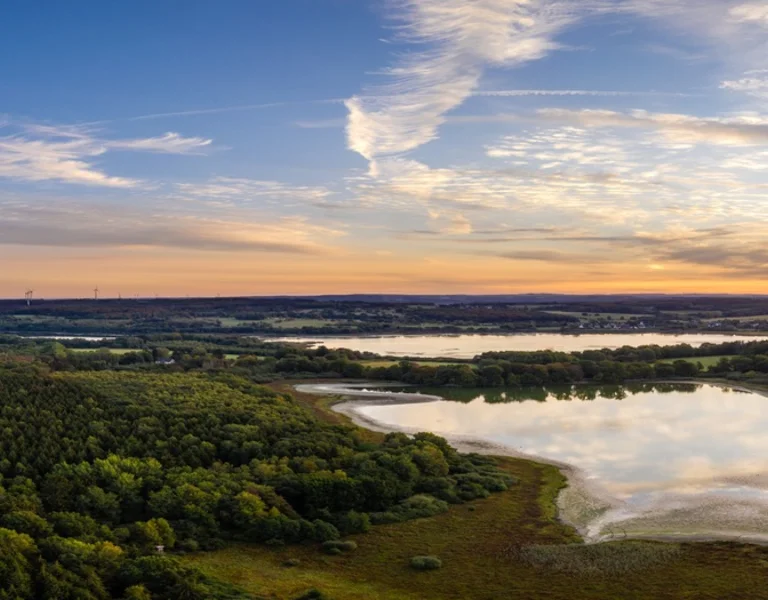 Panoramic aerial view of the Müritz National Park landscape at sunset, featuring lakes and forest.