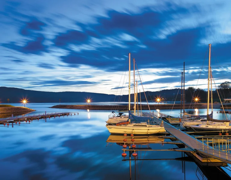 Sailboats docked at Lipno Marina under a evening sky.