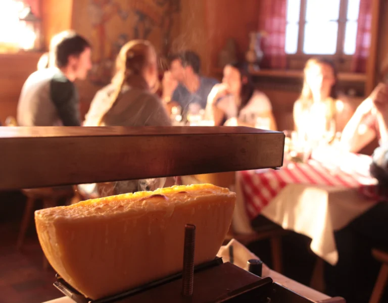 Melted Raclette du Valais AOP served in the alpine setting of the Grand Entremont, highlighting the authentic flavors of Swiss mountain gastronomy.