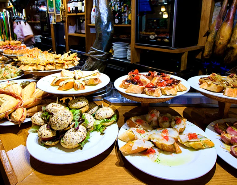 Assorted pintxos displayed on a bar counter in San Sebastián, Spain — traditional Basque tapas showcasing local gastronomy and vibrant food culture.