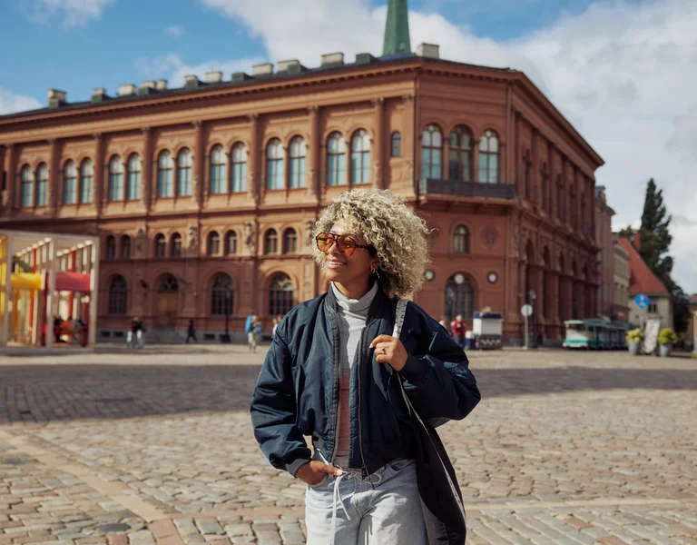 Traveler walking across a historic Dome square in Riga’s Old Town, surrounded by heritage buildings.