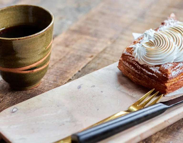 Scandinavian coffee break with artisan coffee and a flaky pastry topped with meringue in a cosy Danish café.