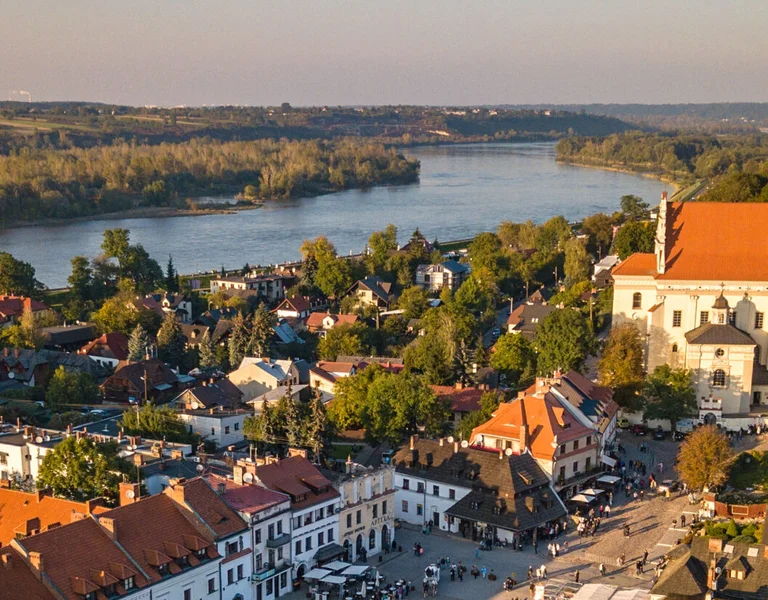 Riverside town with historic buildings and castle ruins at sunset