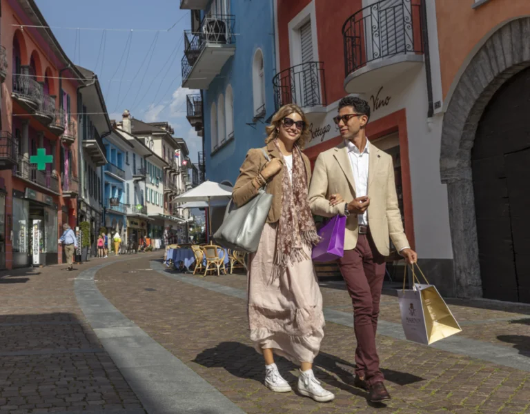 Couple walking with shopping bags on a colorful European street.