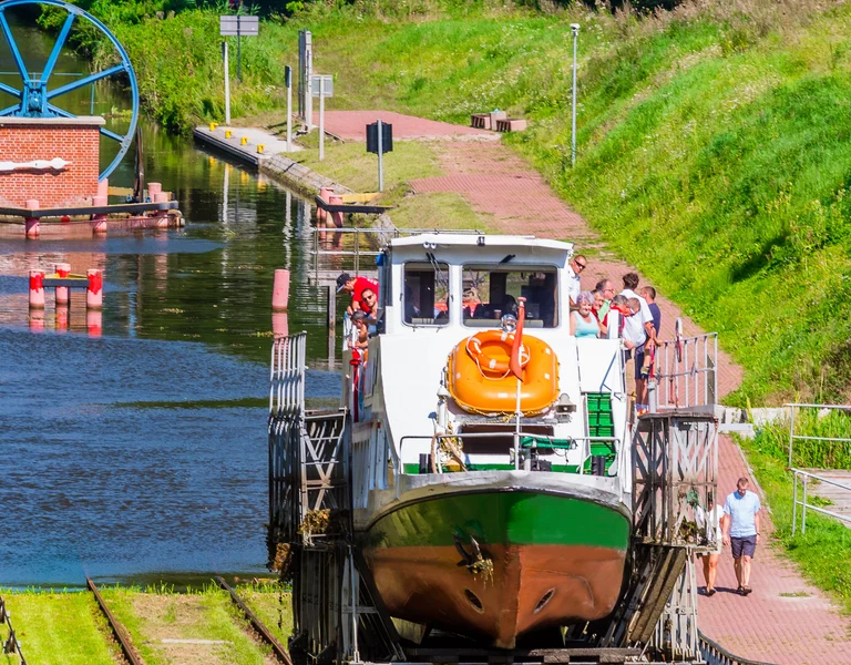 A boat on a canal elevator with green hills and trees surrounding the waterway.