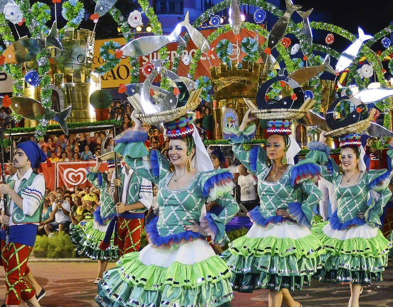 Dancers in colorful costumes performing at a lively outdoor festival at night.
