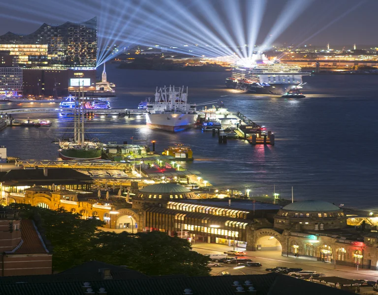 Colorful city waterfront at night with bright lights and boats on the water.