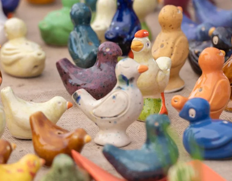 Colorful ceramic bird figurines arranged closely together on a table.