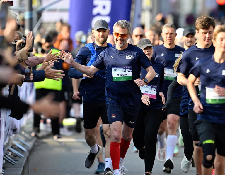Runners in a race high-five spectators along the street.