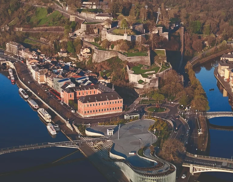 Aerial view of a city with a river, bridges, and historic buildings surrounded by hills.
