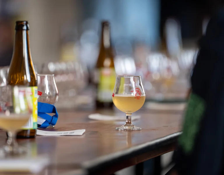 Beer glasses and bottles on a wooden table in a casual indoor setting.