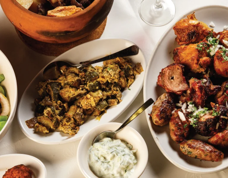 Assorted dishes on a table, including salad, grilled meats, and sides.