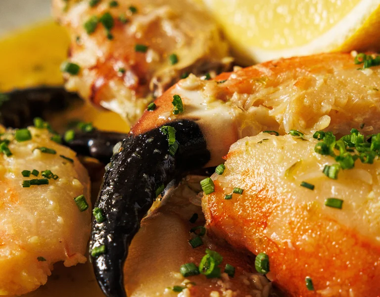 Crab claws in sauce garnished with chopped herbs and a lemon wedge