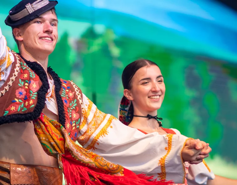 Two dancers in colorful traditional costumes performing on stage.