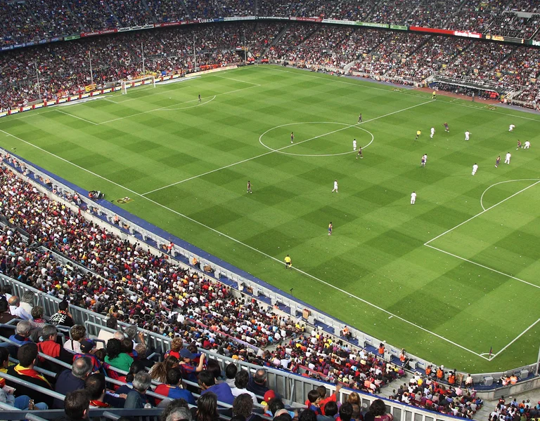 Full soccer stadium with crowds watching a match on a green field.