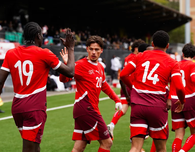 Soccer players in red uniforms celebrating on the field.