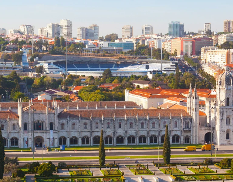 Panoramic view of Jerónimos Monastery with city buildings in the background.