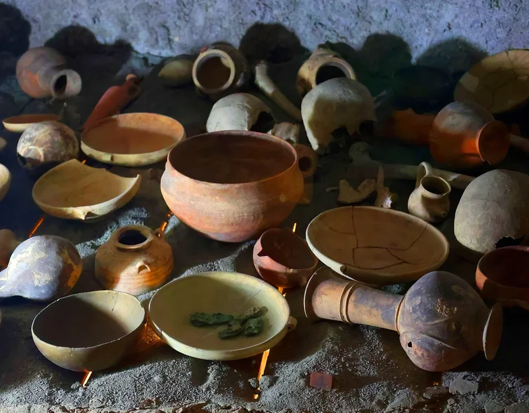 Various clay pots and bowls arranged on a rough stone surface in dim light.