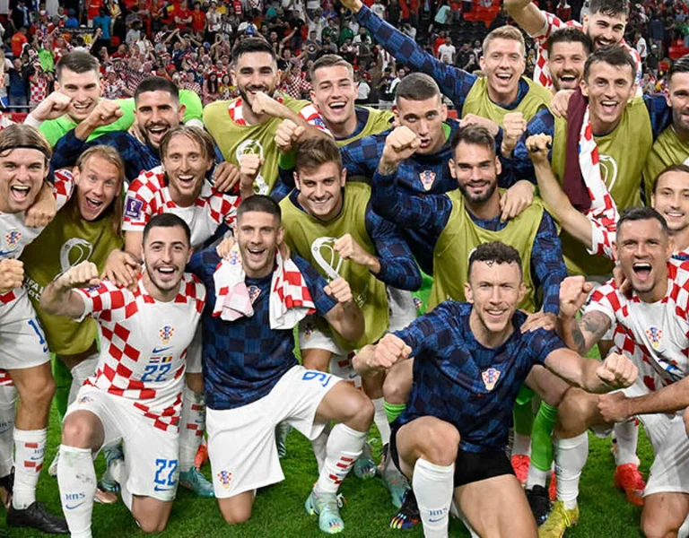 Croatian soccer team celebrates on the field, smiling and posing for a group photo.