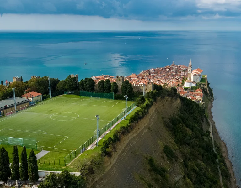 Soccer field on a cliffside overlooking the sea near a coastal town