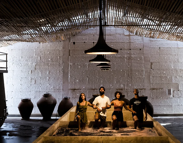 People sitting together in a dimly lit, industrial-looking room with high ceilings.