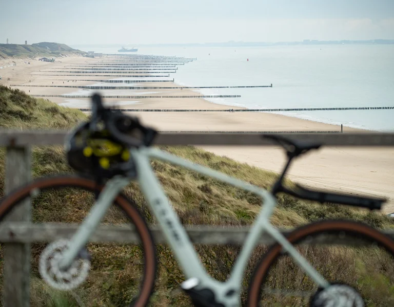 Blurry bicycle in front of a sandy beach and calm sea on a cloudy day.