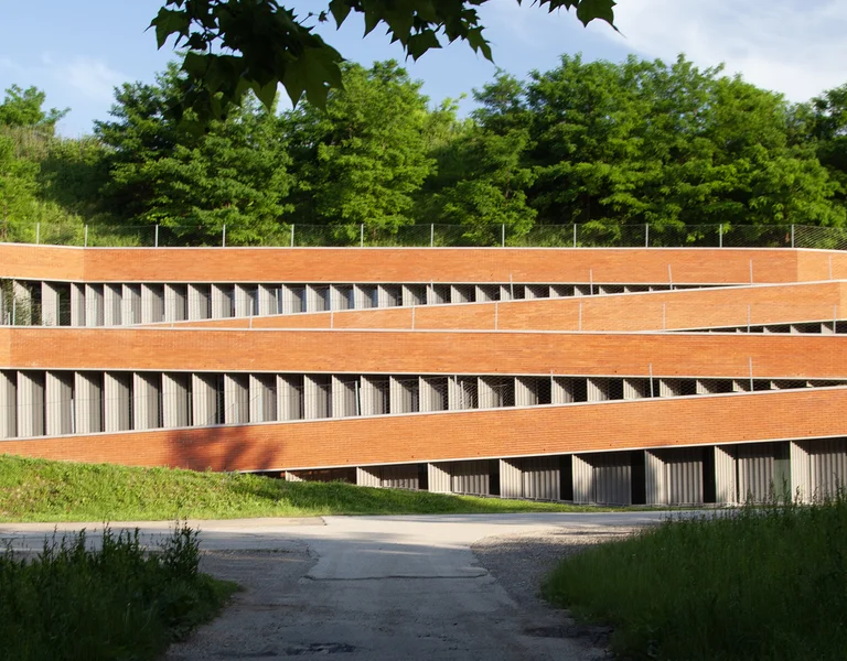 Modern building with layered, slatted wood facade surrounded by greenery and trees.