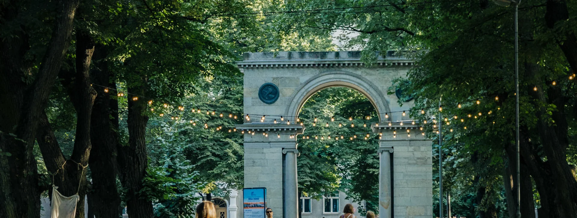 A person walking a dog on a leash at Viesturdārzs Park in summer, Riga.