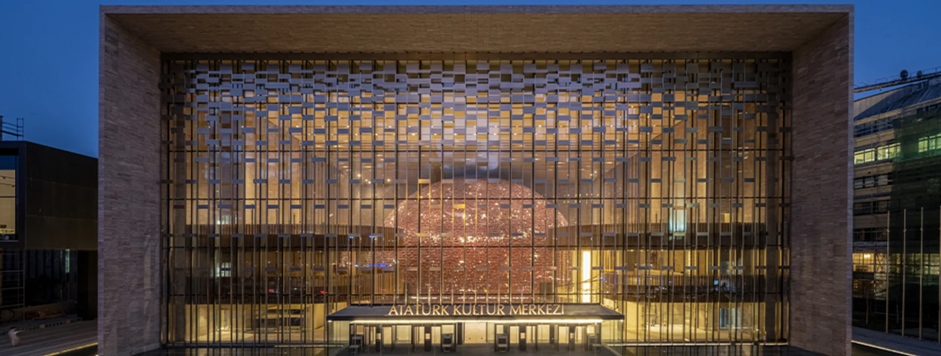 Zeugma Mosaic Museum facade with geometric pattern illuminated at dusk, sign reads "Atatürk Kültür Merkezi".