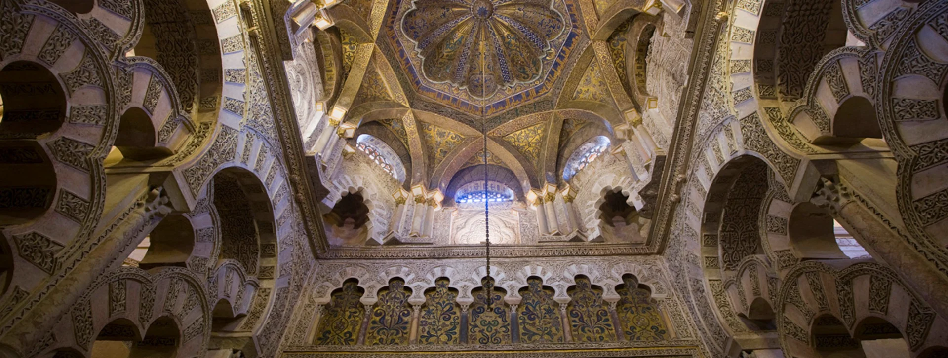 Intricate Islamic architecture features a beautifully crafted ceiling with floral motifs and arches in a historic mosque.