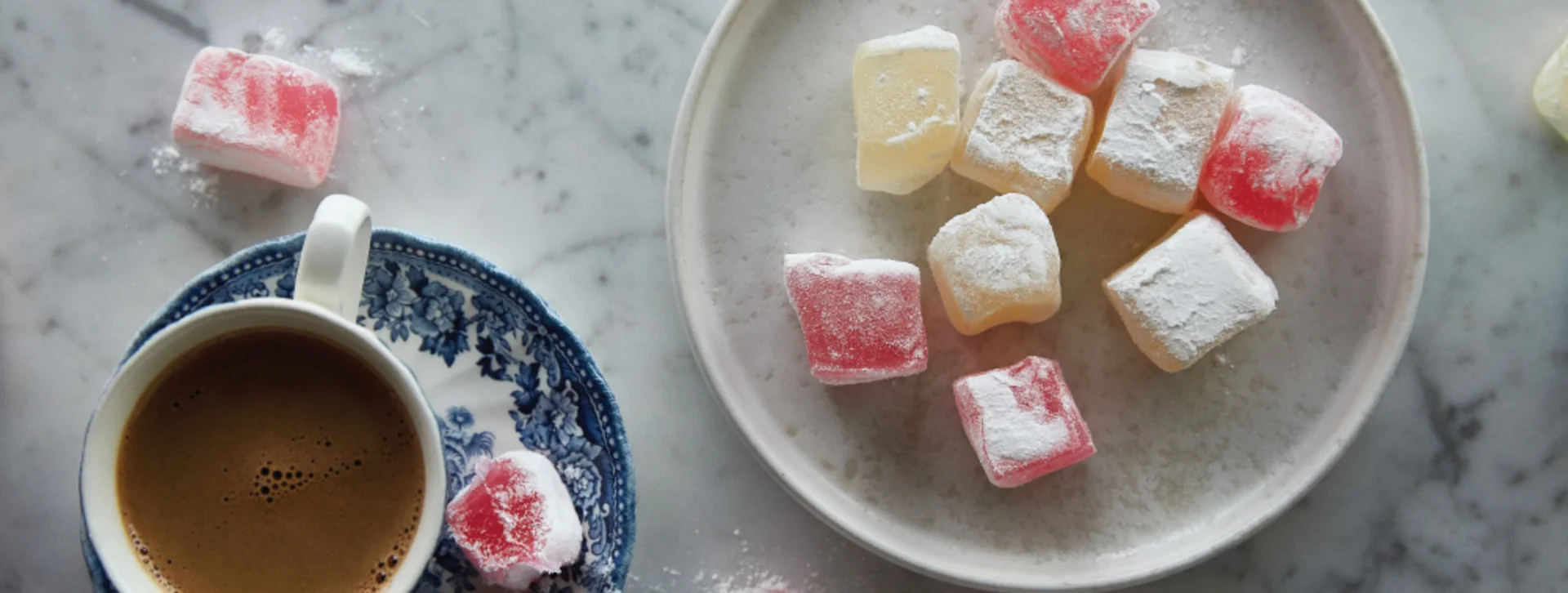 Traditional Cypriot sweets served on a plate alongside a cup of coffee.