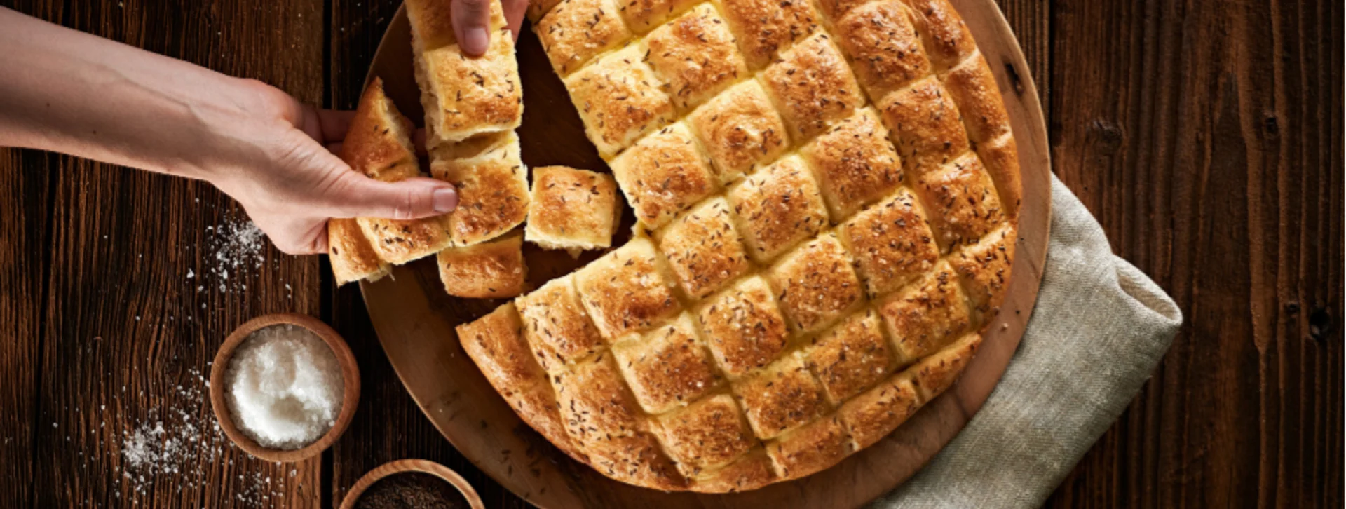 Top view of hands cutting freshly baked Bela Krajina flatbread, a Slovenian culinary tradition.